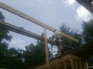 Carpenter setting a ridge beam over a new addition frame — Ice Dam Removal by Roofing Brothers in Burton
